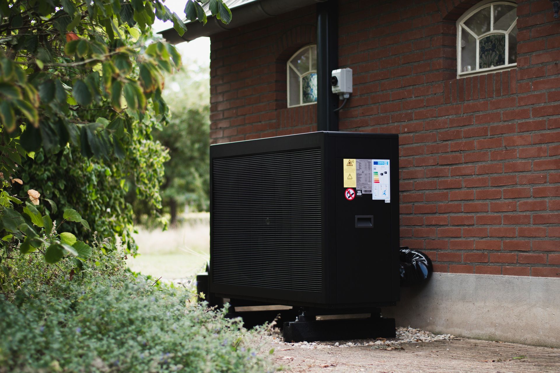 Zwarte Next warmtepomp naast woning